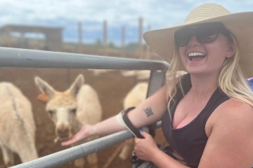 a woman standing next to a fence